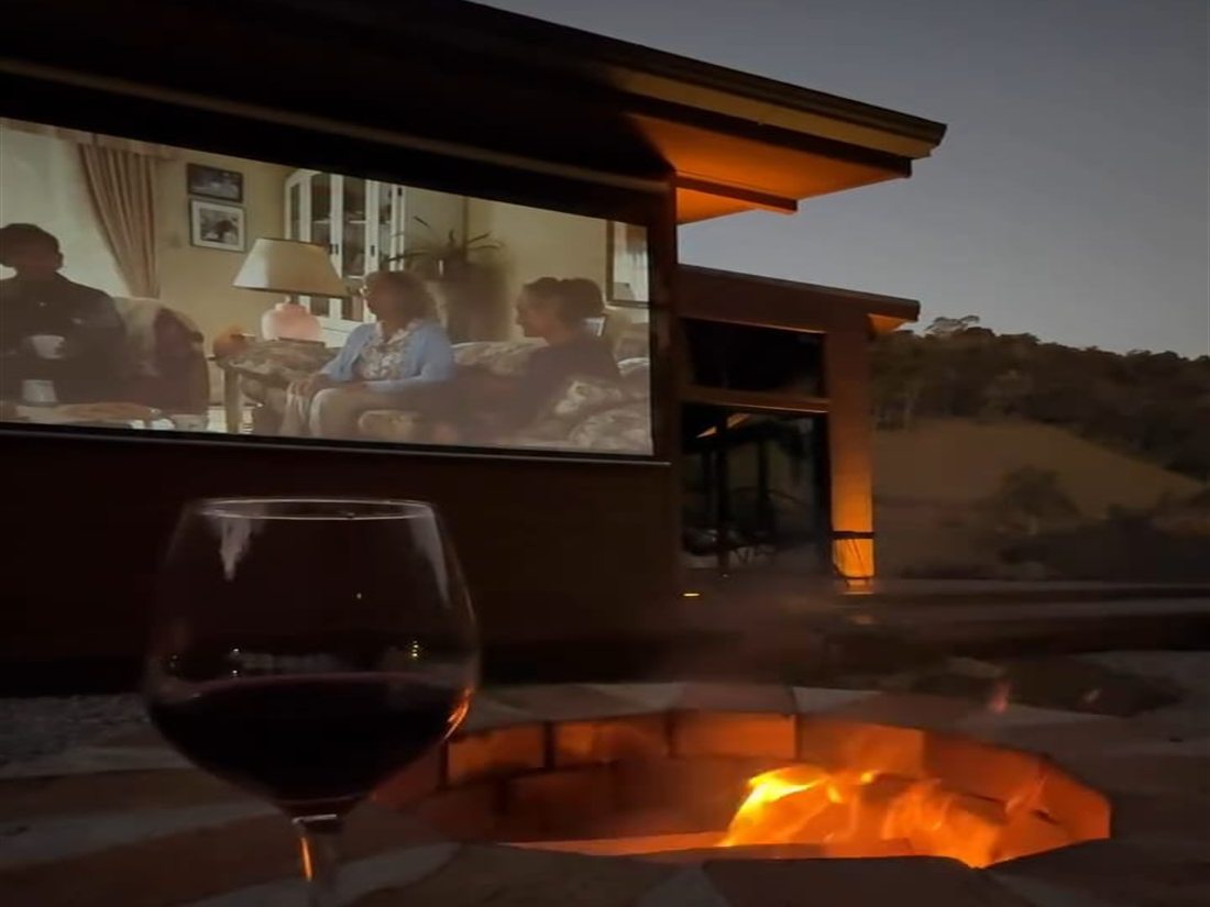 Bonfire burning under a starry sky with guests seated around it